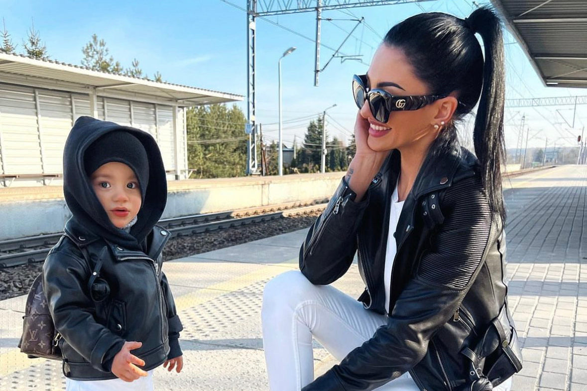 Woman and child at a train station wearing black lambskin leather jackets.