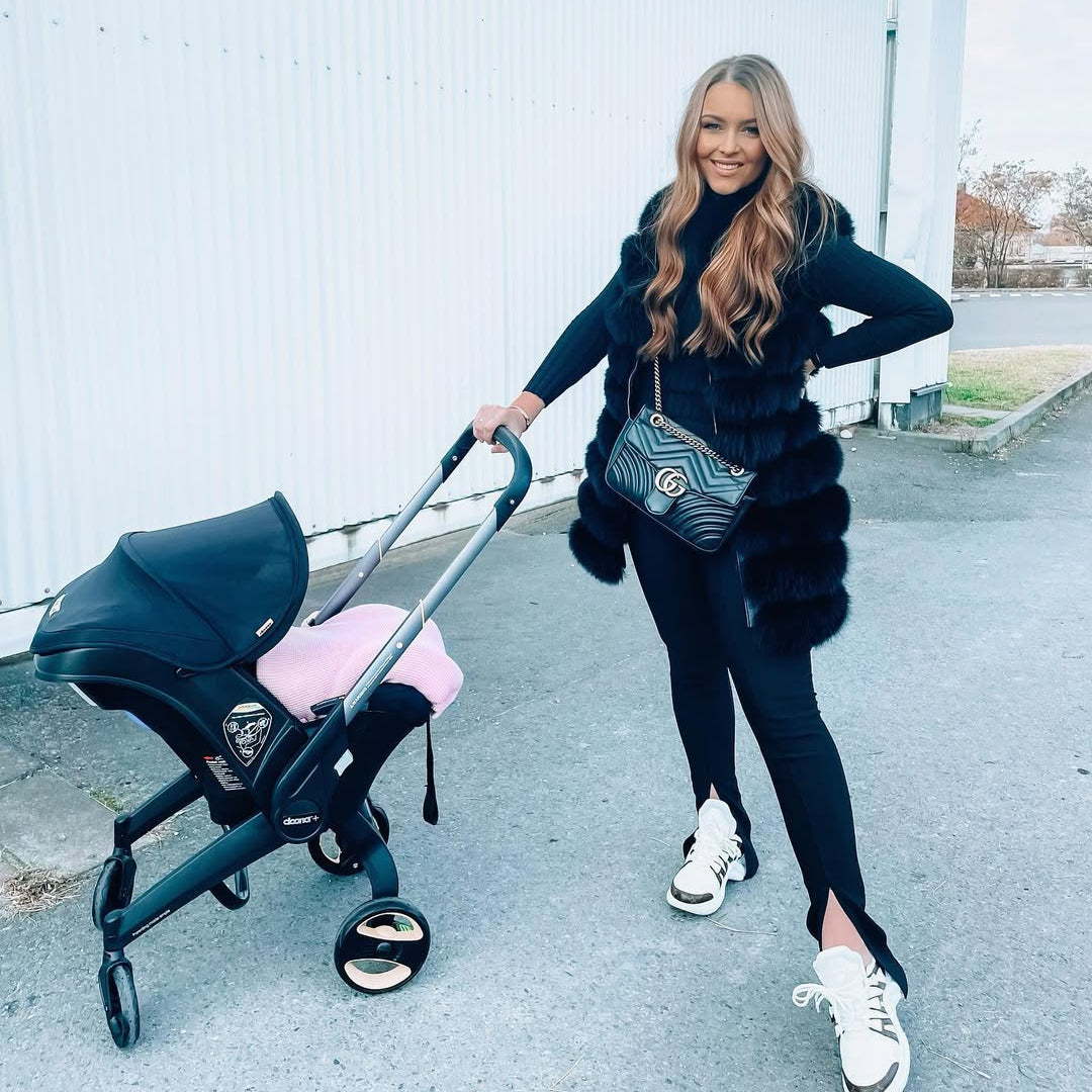 Woman with a fur coat pushing a stroller in an urban setting