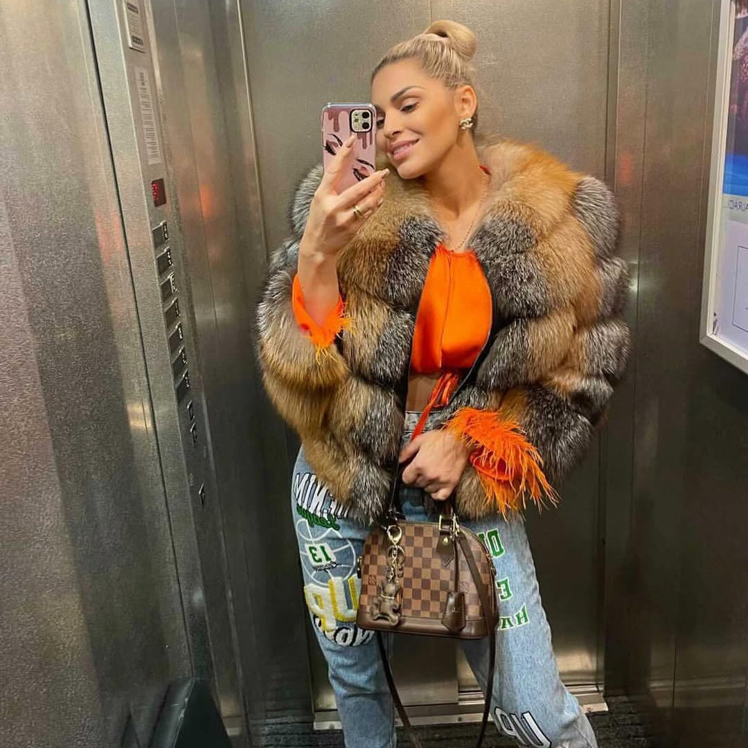 Person wearing a fur coat and orange top in an elevator